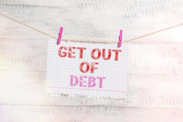 Writing note showing Get Out Of Debt. Business photo showcasing changing spending habit Learn to budget Prioritizing debts Clothesline clothespin rectangle shaped paper reminder white wood desk. - Photo, Image