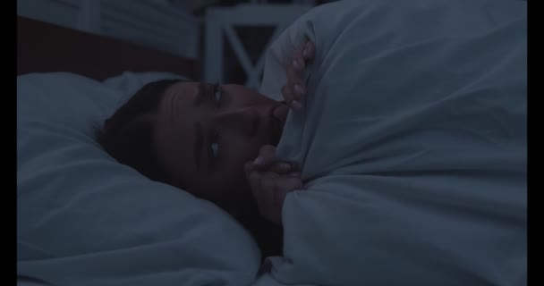 Aggódó lány fekszik ébren az ágyban, eltakarja arcát takaróval - Felvétel, videó