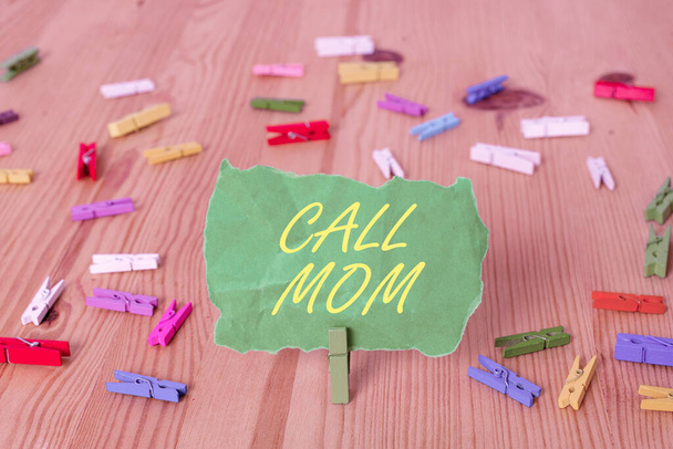 Word writing text Call Mom. Business concept for Attempting to communicate with the mother using the smartphone Colored clothespin papers empty reminder wooden floor background office. - Photo, Image