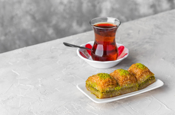 БАКЛАВА. Традиционные турецкие десерты Баклава с турецким чаем. Хрустящая фисташковая пахлава на белой тарелке
. - Фото, изображение