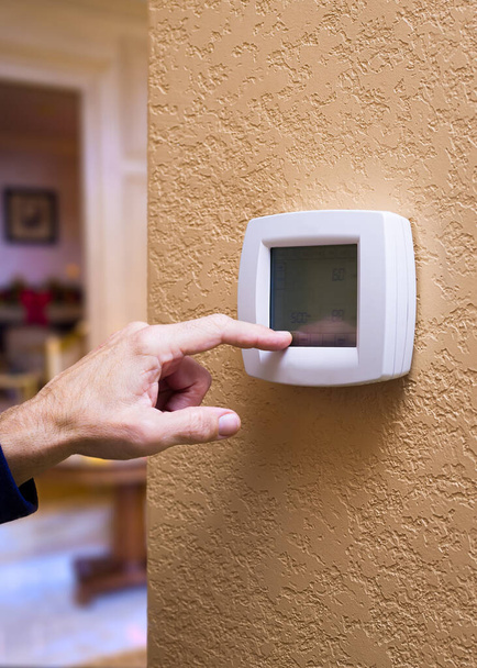 Primer plano de una mano masculina presionando un botón en un termostato digital
 - Foto, imagen