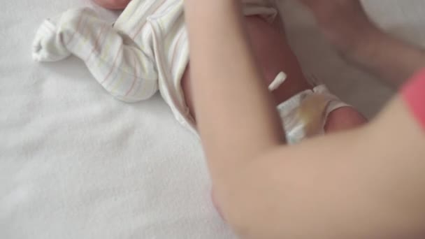 Baby, kindertijd, moederschap, familie, thygiëne, geneeskunde en gezondheid concept - close-up mama handen uitkleedt neemt bodysuit pasgeboren wakker baby top uitzicht op witte achtergrond in de eerste minuten van het leven - Video