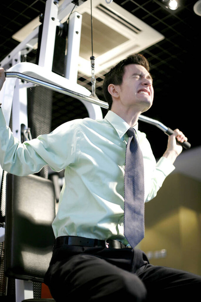 Businessman lifting weight in the gymnasium - Фото, зображення
