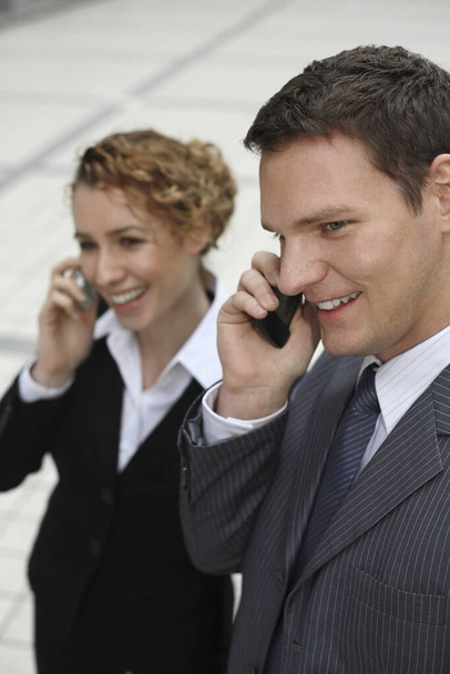 Businessman and businesswoman talking on the phone - Photo, image