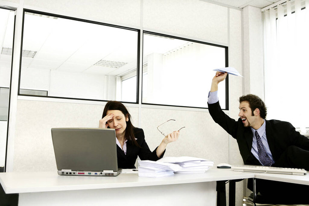 Businessman throwing a paper plane at his stressed up colleague - Fotó, kép