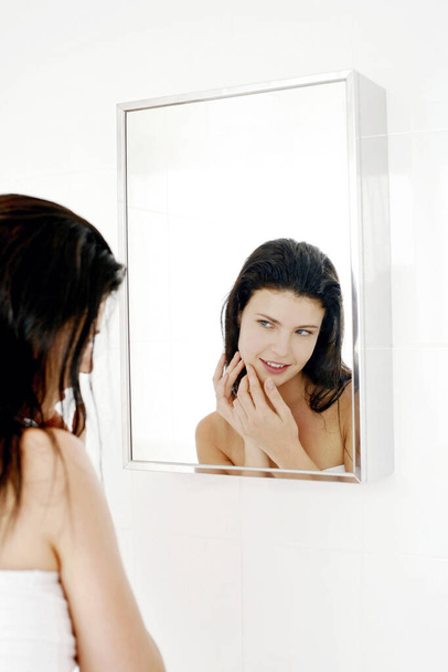 Woman checking her face in the mirror - 写真・画像