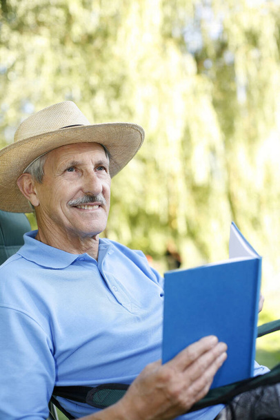 Senior man with hat reading book - Foto, imagen