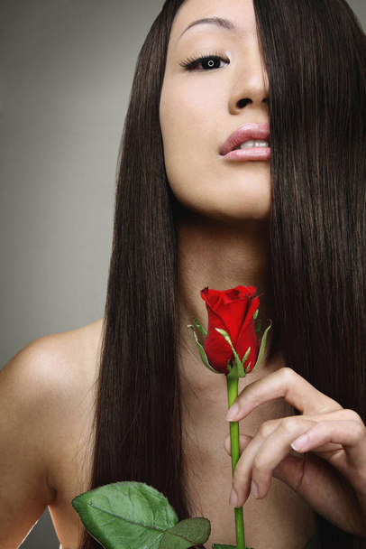 Woman with long hair holding a red rose - Photo, Image