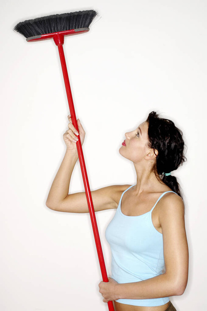 Woman cleaning ceiling with a broom - Фото, зображення