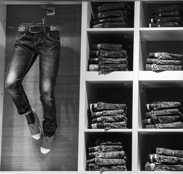 Shop window of jeans clothes. The mannequin is dressed in jeans, and on the shelves of the shelves are stacks of jeans. - Photo, Image