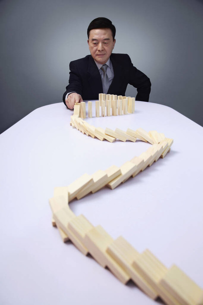 Businessman playing with wooden blocks arranged on the table - Foto, afbeelding