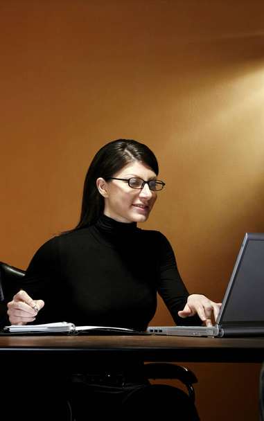 Businesswoman writing while using laptop - Foto, Imagen