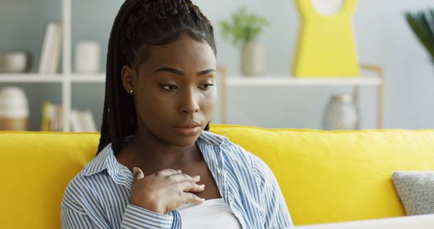 魅力的なアフリカ系アメリカ人の若い女性は、ラップトップコンピュータでチャットし、彼女が画面上で読んでいるか、見ている何かからショックを受けています。家で。室内 - 写真・画像