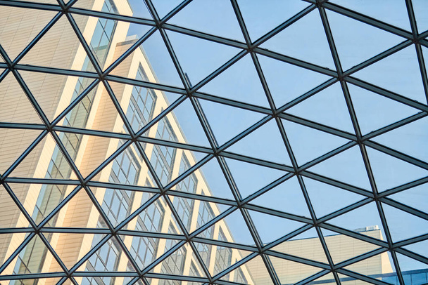 Прозрачный потолок в бизнес-центре. Стеклянные треугольные окна. Сетчатая структура архитектуры. Абстрактный геометрический рисунок стекла в рамке - Фото, изображение
