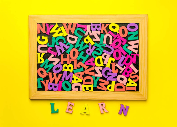 Multicolored wooden letters Tightly placed inside a wooden frame blackboard and colorful lettering Learn on the Yellow Background. Education and back to school concept - Photo, Image