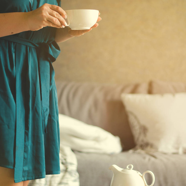 Cozy home interior with teapot and woman holding cup of tea. - Foto, Bild