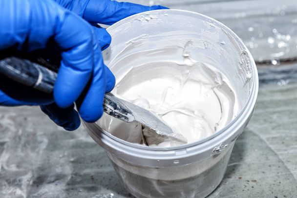 Ручное смешивание белой штукатурки с лопаткой
 - Фото, изображение