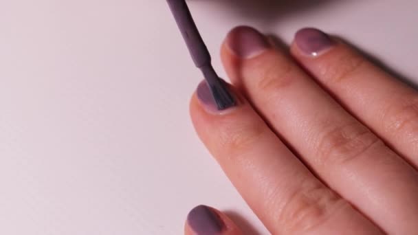 少女自身が爪に薄い紫色のゲルのポリッシュを塗ります。自宅でのマニキュア. - 映像、動画