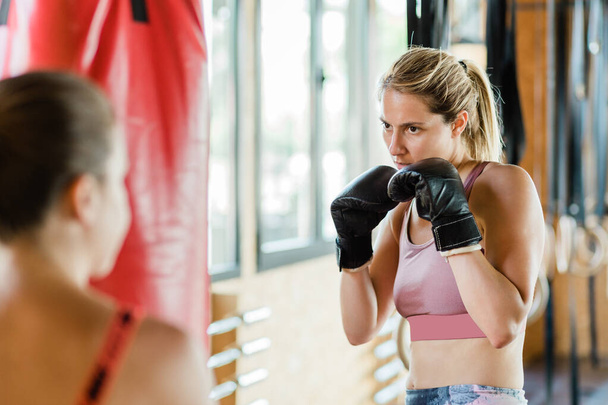 Spor salonundaki genç bayan boks yapıyor. - Fotoğraf, Görsel