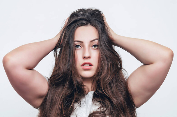Портрет девушки с длинными темными волосами, взъерошенными волосами на голове, поднятыми руками
. - Фото, изображение