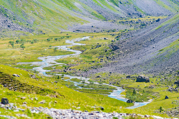Ruisseau alpin dans une vallée idyllique au milieu de rochers et de prairies verdoyantes, réservoir naturel d'eau douce à haute altitude sur les montagnes.  - Photo, image