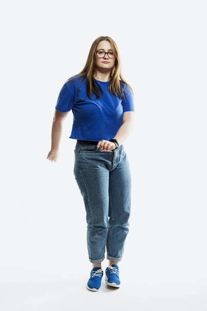 Young girl in a blue tank top and jeans. Full height. Isolated on spruce background. Vertical - Foto, Imagem