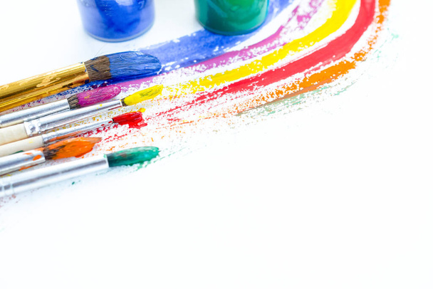 blikjes gekleurde verf gouache met gekleurde strepen en penselen - Foto, afbeelding