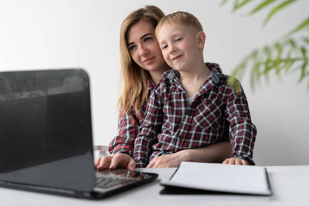 The child and mother study remotely. A woman helps her child. Online training. Home education and independence. Schoolchildren study during quarantine. Work with a laptop. Place for text. - Photo, Image