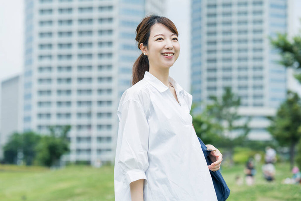 aziatische vrouw het dragen van een wit shirt en het nemen van een wandeling in een ontspannen sfeer - Foto, afbeelding