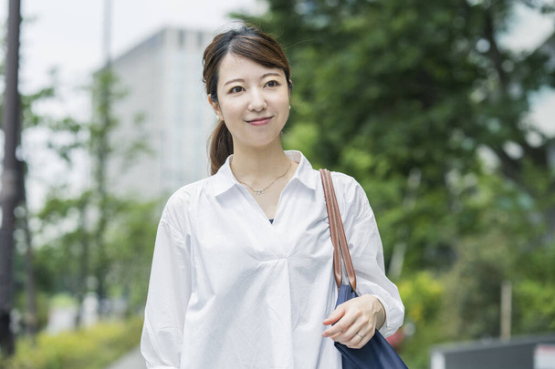 Femme asiatique portant une chemise blanche et faisant une promenade dans une atmosphère relaxante - Photo, image