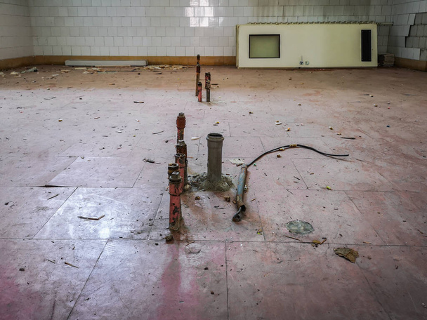 Tuberías de agua en el suelo en la vieja cocina y puertas liadas contra la pared en el viejo hospital abandonado
 - Foto, imagen