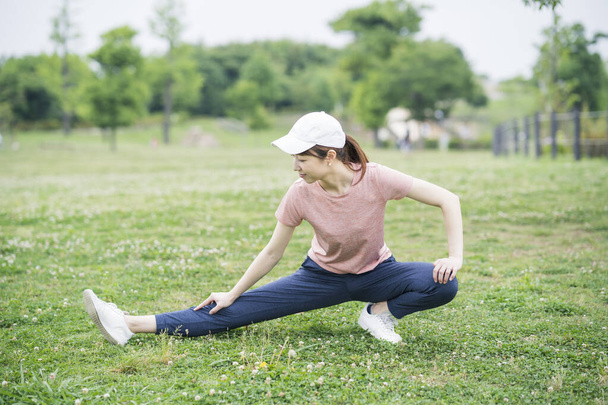 Aziatische jonge vrouw draagt sportkleding en sport in het park - Foto, afbeelding