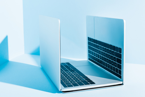 modern laptops on blue workplace in sunlight - Foto, afbeelding