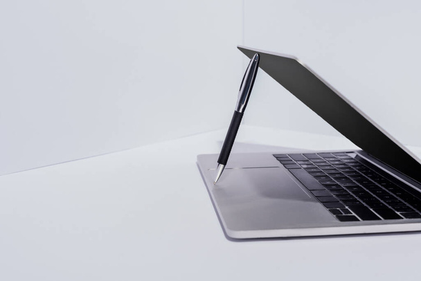 pen in moderne laptop op witte achtergrond - Foto, afbeelding
