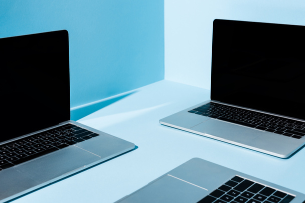modern laptopok üres képernyőkkel kék háttéren - Fotó, kép