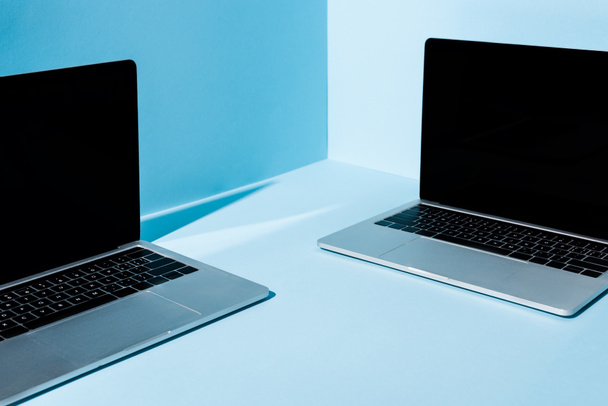 modern laptops with blank screens on blue background - 写真・画像