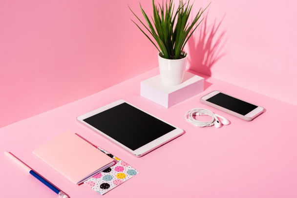 modern gadgets with blank screens, stationery, earphones and plant on pink background - Photo, Image