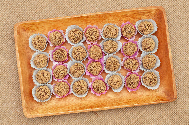 Traditional Brazilian homemade candy called "Brigadeiro de Amendoim" in Brazilian Portuguese. Made with crushed peanuts, margarine and condensed milk. Top view. Jute fabric background. - Photo, Image