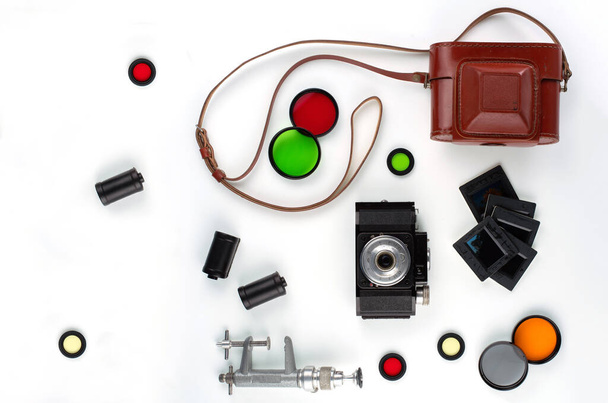 Vintage aparat fotograficzny, etui z piórami, kasety, filtry kolorów, slajdy i mini stojak izolowany na białym. - Zdjęcie, obraz