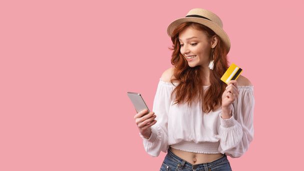 Lány gazdaság telefon és hitelkártya álló rózsaszín háttér - Fotó, kép