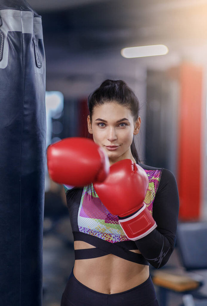 Millennial boxeador feminino em luvas de bola de perfuração no clube de esportes
 - Foto, Imagem