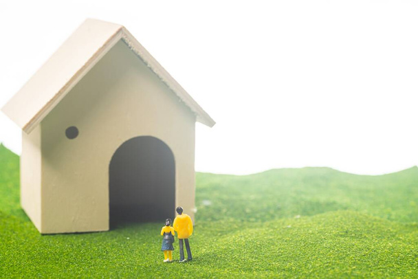Miniature couple figures in front of a toy house, buying or owning a house concept - Photo, Image