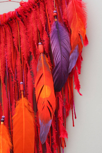 Closeup details modern dreamcatcher with painted colorful feathers on gray background - Photo, Image
