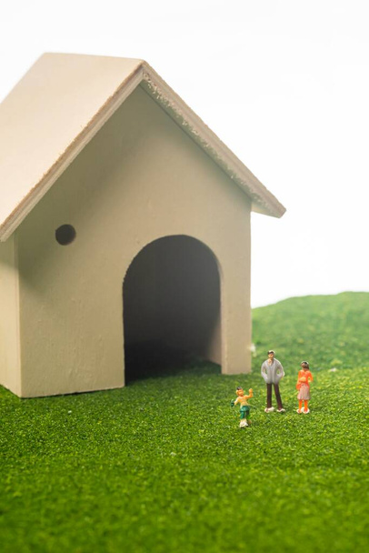 Миниатюрные люди из игрушечного домика. Счастливая семейная концепция: семья перед домом
 - Фото, изображение