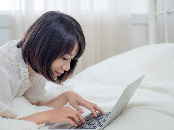 Femme couchée au lit avec ordinateur portable - Photo, image