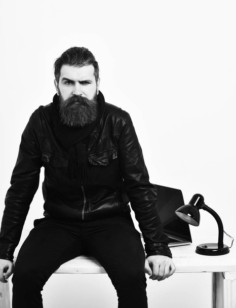 Bearded brutal caucasian hipster sitting on table with laptop on - Foto, Imagem