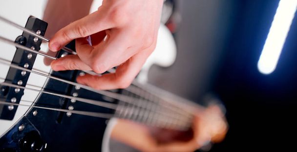 Κοντινό πλάνο ενός ατόμου που κρατάει και παίζει μπάσο κιθάρα - Φωτογραφία, εικόνα