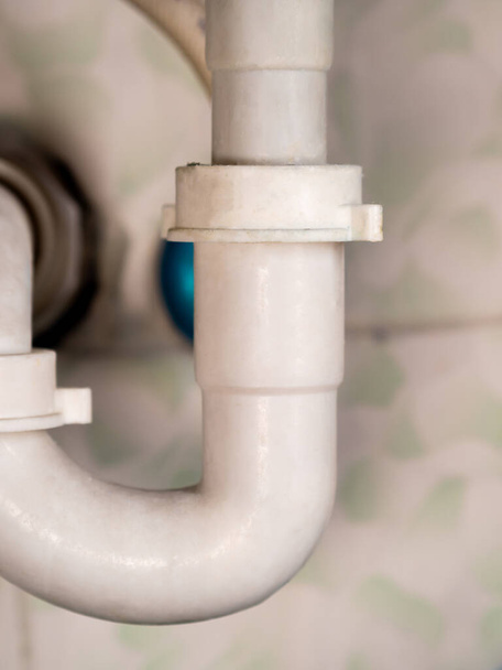 witte badkamer afvoerbuizen en keramische wand close-up - Foto, afbeelding