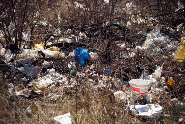Yatay görüş. Çöp, plastik, torbalar ve polyester saçılmış ve gün ışığında kuru çimlere atılmış. Ekoloji kavramı, doğaya kayıtsızlık. - Fotoğraf, Görsel