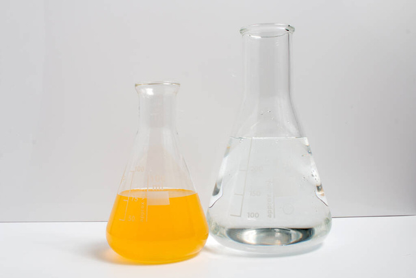 Glaswerk voor laboratoria gevuld met chemische vloeistoffen op een witte achtergrond. Wetenschappen. - Foto, afbeelding